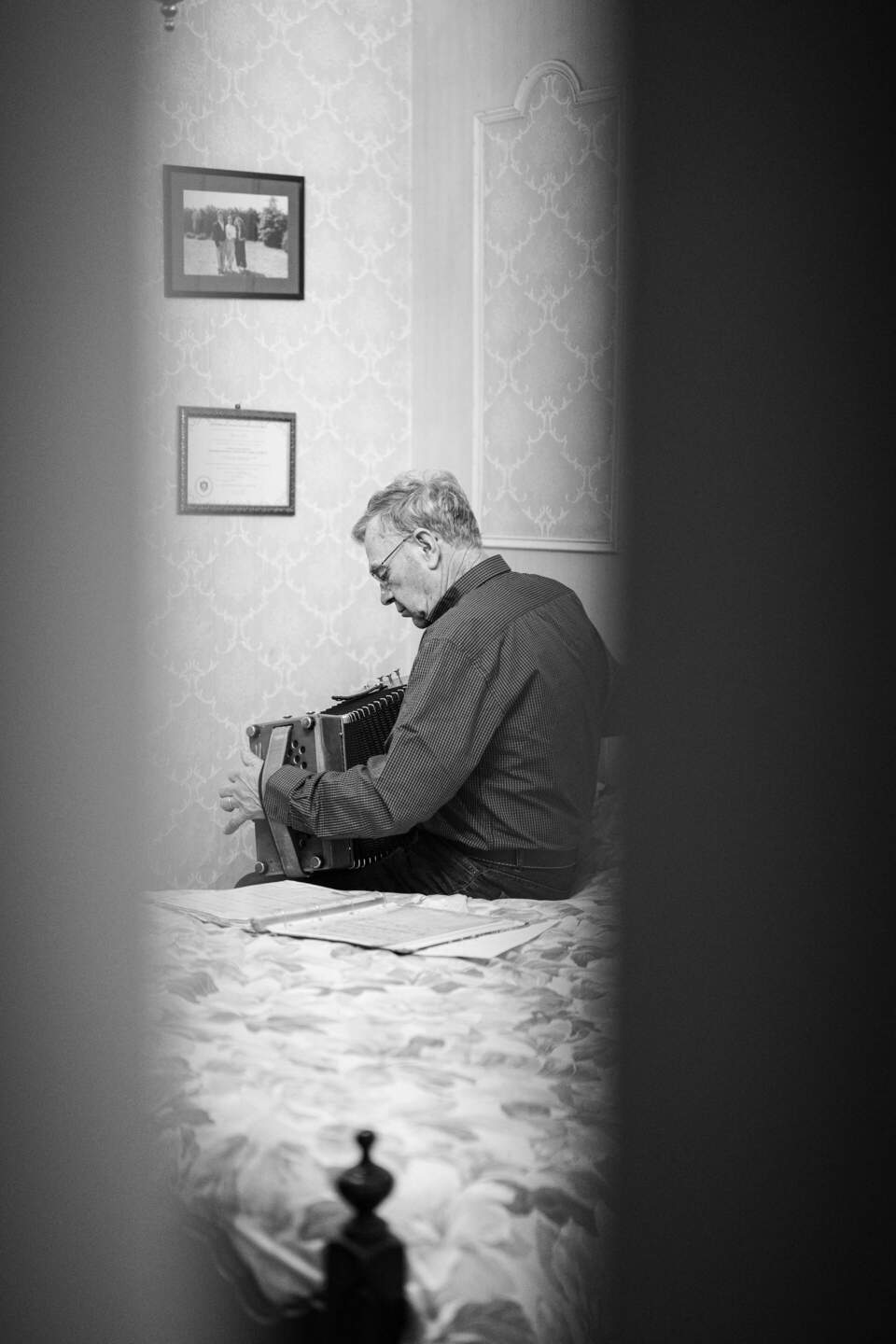 Elderly man playing accordion in his room