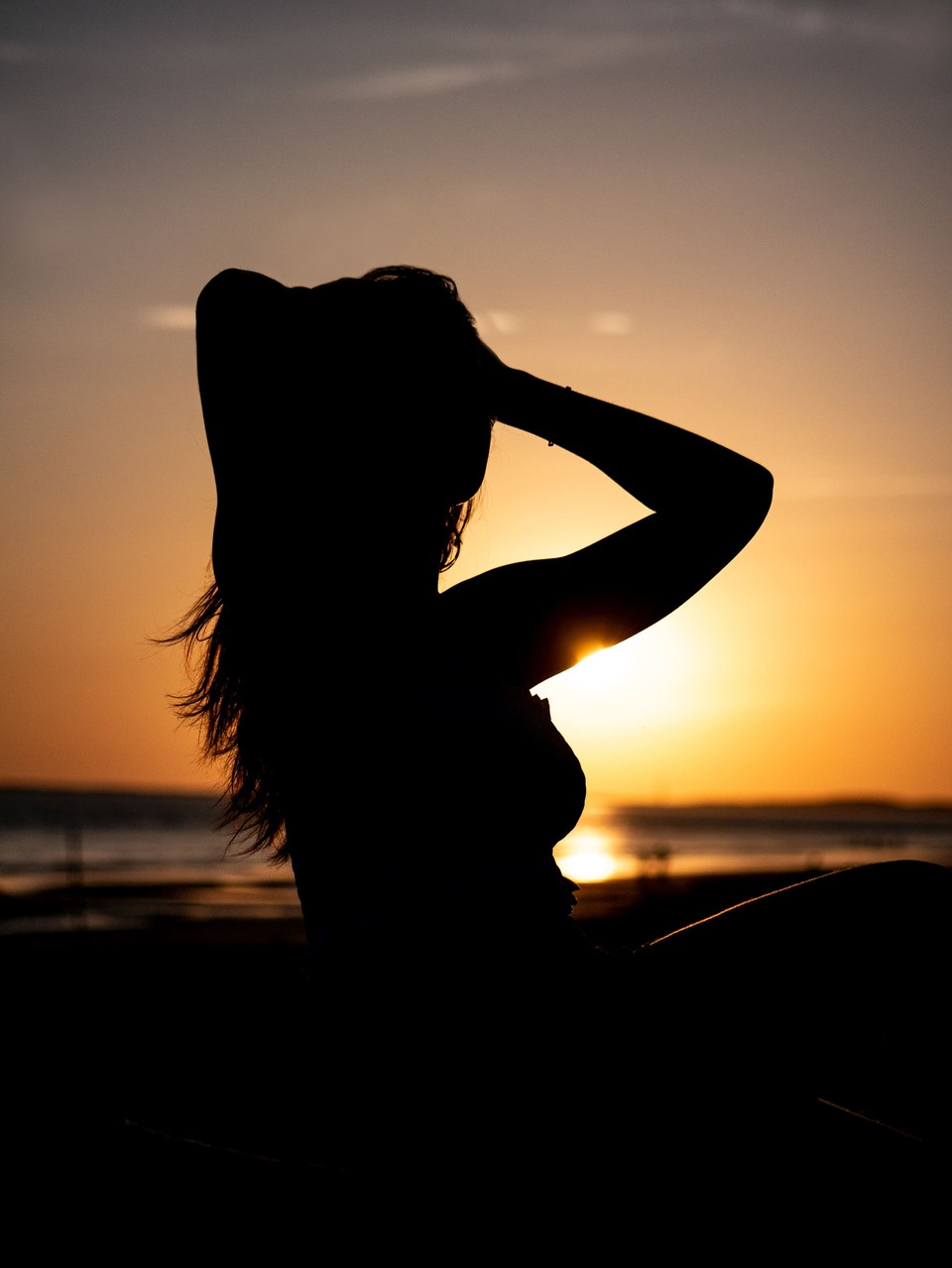 Silhouette d'une femme en contre jour sur la plage