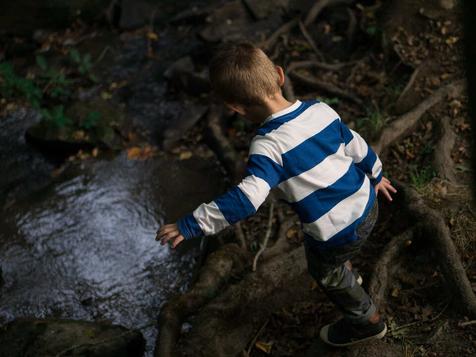 Child playing in a highly contrasted water puddle